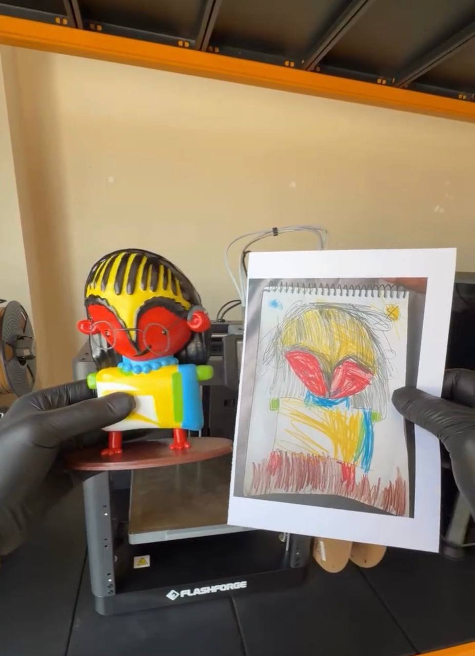 A hand-painted figurine with glasses beside the original crayon sketchpad drawing